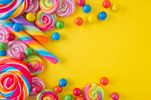 istock Various lollipops and round candy in bright and bold colours on a yellow background, with space for text 1795295050