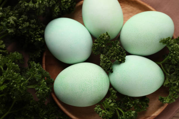 A charming image featuring a group of pastel-hued eggs arranged in a white bowl set on a rustic wooden surface.