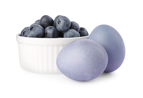Colorful Easter eggs painted with natural dye and fresh blueberries on white background