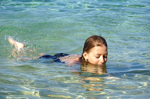 Summer joys and a little girl playing in the shallow and clear sea water during summer