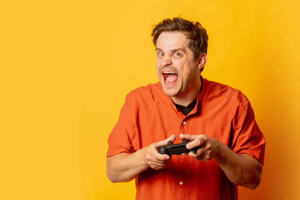 istock Excited guy play with game cotroller on yellow background 1795332777
