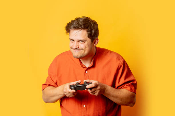 istock Excited guy play with game cotroller on yellow background 1795332786