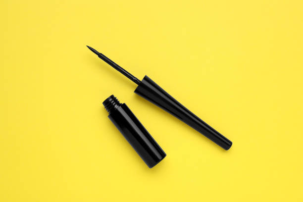 istock Black eyeliner on yellow background, flat lay. Makeup product 1795337964