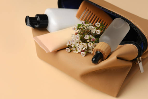 istock Preparation for spa. Compact toiletry bag with different cosmetic products and flowers on light brown background, closeup 1795339040