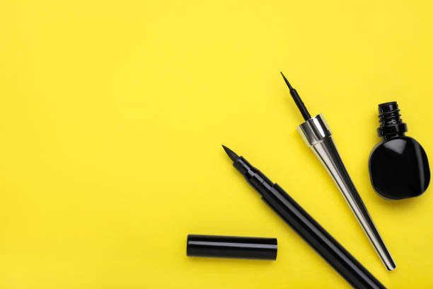 istock Black eyeliners on yellow background, flat lay. Makeup product 1795340786