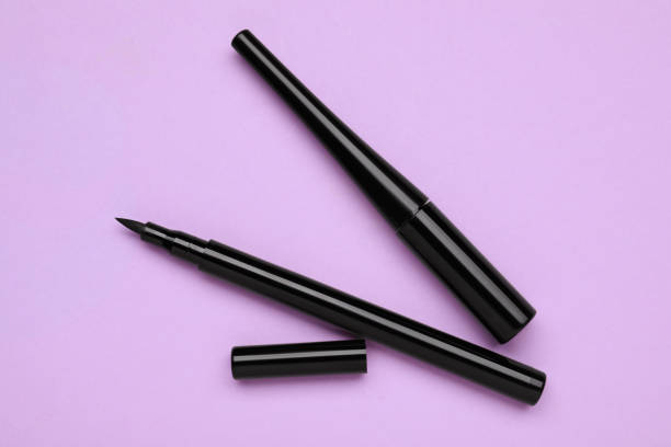istock Black eyeliners on lilac background, flat lay. Makeup product 1795341362
