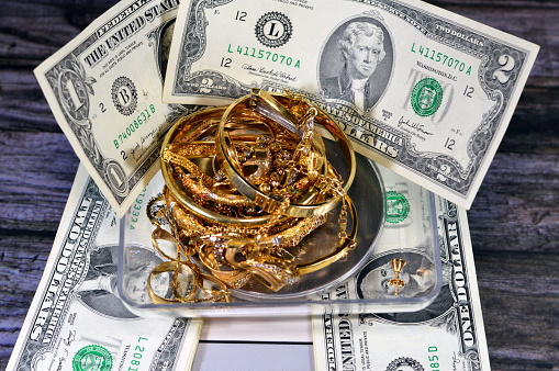 Pile stack of gold on a digital accurate scale in grams, bracelets with USD American dollars money, gold price concept, precious metal, savings, selling, buying and purchasing precious metal of gold, selective focus