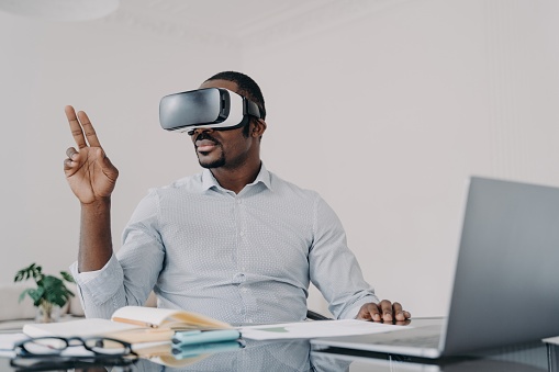 Man in VR headset gesturing, exploring virtual reality at his desk