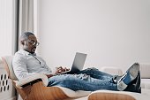Relaxed businessman in glasses using a laptop, comfortable in a modern chair