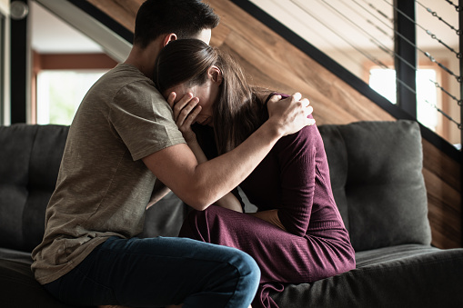 Husband comforting his sick wife at home. Receiving bad news.