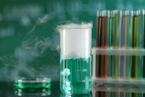 Laboratory glassware and test tubes with colorful liquids on glass table. Chemical reaction