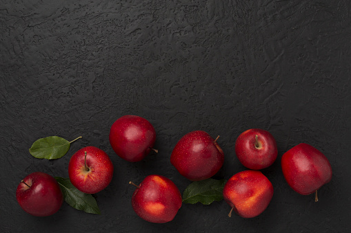 Fresh red apples with leaves on concrete background, top view
