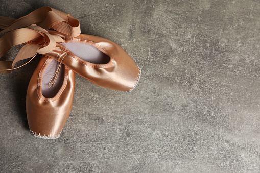 Ballet shoes. Elegant pointes on grey textured background, flat lay with space for text