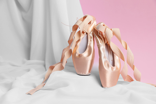 Ballet shoes. Stylish presentation of elegant pointes on pink background. Space for text