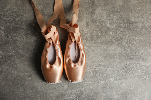 Ballet shoes. Elegant pointes on grey textured background, flat lay