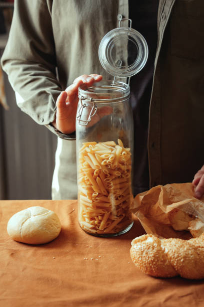 istock Man with pasta penne and bread on table in kitchen 1795379176