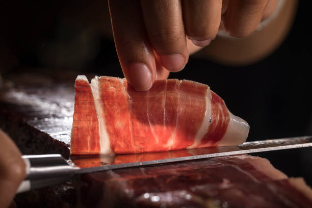 istock Spanish acorn-fed Iberian ham. Iberian ham cutter hand cutting slice for tasting. Typical high quality slice of Iberian ham with its veins and fat. 1795379739