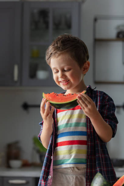 istock Little kid eating watermelon in kitchen 1795382520