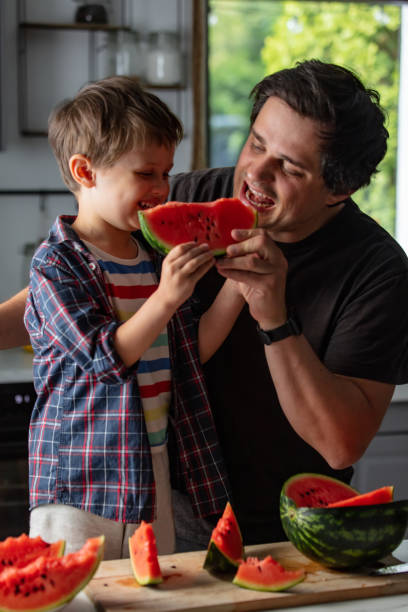 istock Father and son eating watermelon in kitchen 1795382696