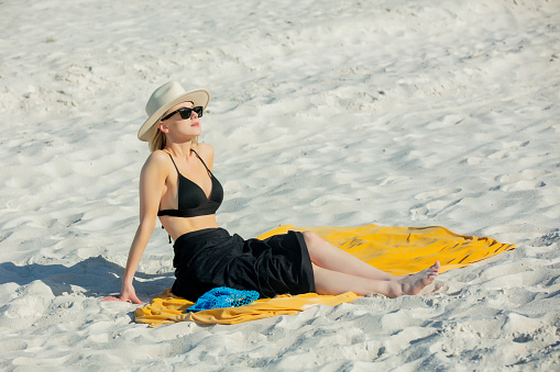 Woman sits on beach in bikini and realx