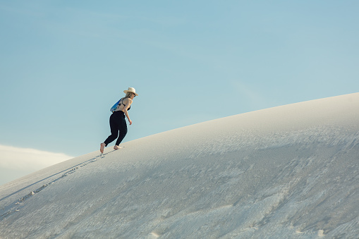 Woman walking on white  sand dune in desert in summer