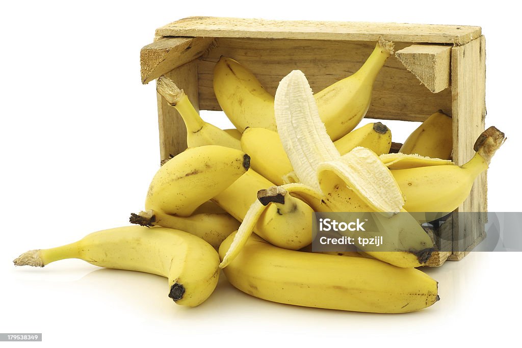 fresh bananas and a peeled one fresh bananas and a peeled one in a wooden crate on a white background Banana Stock Photo