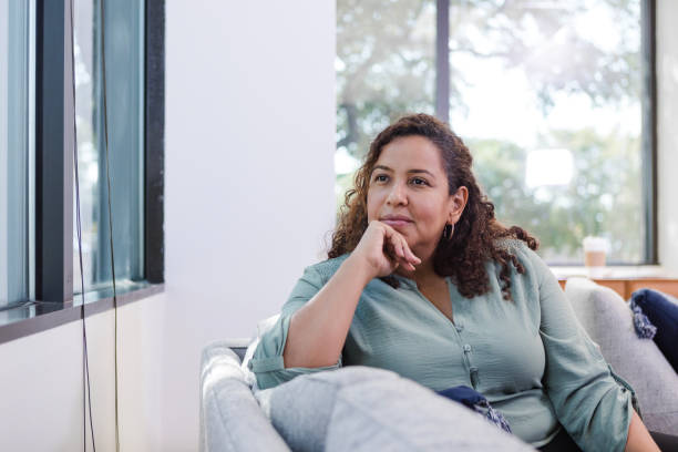 istock Mid adult female gazes out the window while she takes a break from work 1795395205