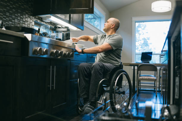 istock Man using a wheelchair puts dishes away in kitchen 1795402703