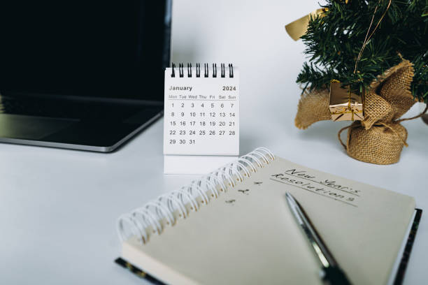 istock open notepad with resolutions for new 2024 year text. Near laptop, calendar and christmas tree 1795403794