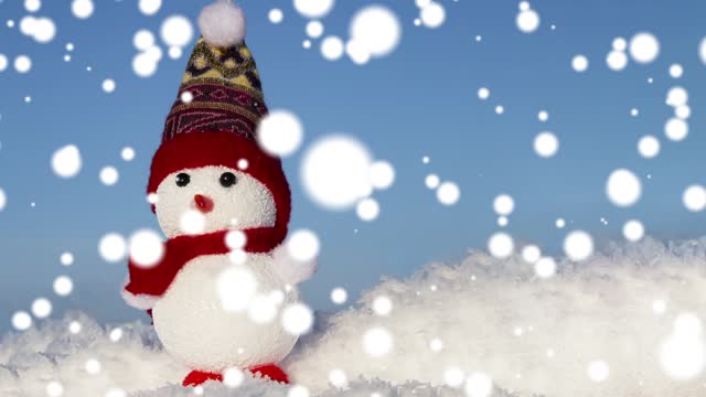 A snowman toy on the snow in a snowfall. Christmas, winter