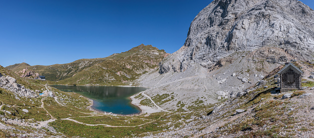 Wide panoramic view, made with multiple images, showing Lake Volaia and its natural environment, under the peak of the majestic mount Coglians, in a September morning with good weather. border area between Italy and Austria