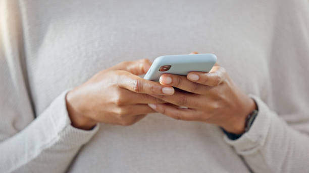 Person holding a phone while texting on social media. One trendy woman writing a quick and convenient text message on an instant chat app. Closeup of a girl browsing content online or on the internet persona, teléfono y manos escribiendo en las redes sociales, la comunicación o las redes en línea en casa. primer plano de los mensajes de texto de los autónomos, el chat o la investigación en la aplicación móvil para teléfonos inteligentes para el
