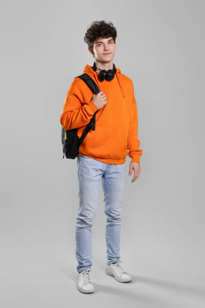 istock Teenage boy with headphones and backpack on light grey background 1795455735
