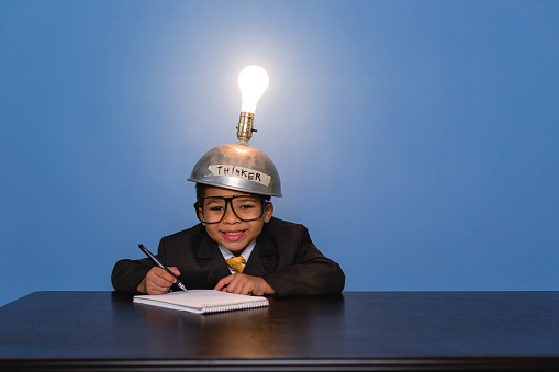 Two young business boys are wearing lightbulb helmets to help them think of the next big idea.