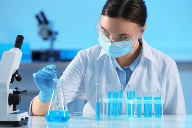 istock Scientist taking sample of light blue liquid and test tubes in laboratory 1795476733