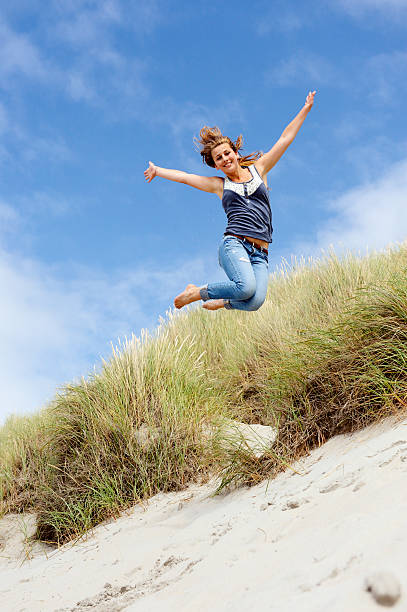 девушка прыжки в дюны - arms outstretched teenage girls jumping flying стоковые фото и изображения