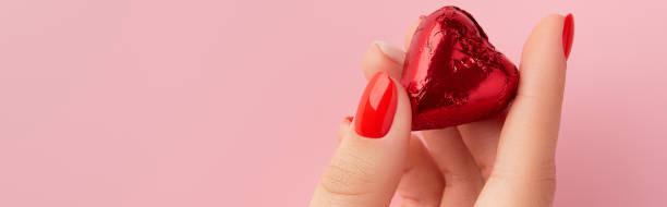 istock Womans hands with red manicure holding candy in heart shape. Valentines day 1795497541