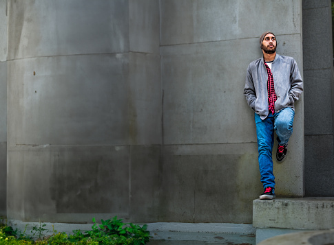 Bearded Homeless Man in His 40s Looking at Camera While Sitting Under the Bridge. Homelessness Social Issues Concept.