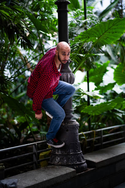 istock Madrid casual: Bald, bearded man, red-checkered shirt, leaning on lamppost, indoor scene 1795499695