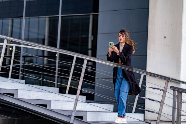 istock Young professional chats, texts, urban backdrop. 1795500260