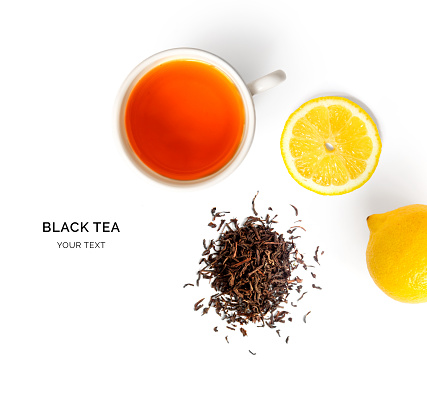Creative layout made of cup of black tea and lemon on a white background. Top view.