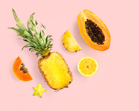 Creative layout made of pineapple, papaya, lemon, carambola on pink background.  Tropical flat lay. Food concept.