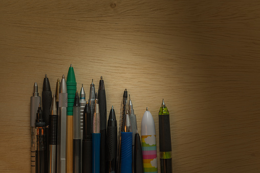 Collection background of pens and pencils on wooden surface. Conceptual image about the work tools of writers, journalist and graphic artists