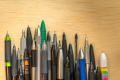 Collection background of pens and pencils on wooden surface. Conceptual image about the work tools of writers, journalist and graphic artists