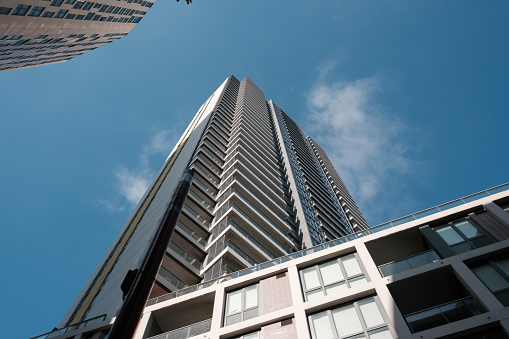 Low angle view of a tall apartment building with blue sky above.