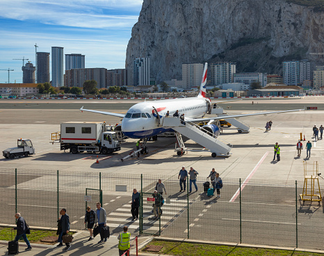 Arriving passengers leaving a British Airways Airbus A320-232 at Gibraltar Airport, with the Rock in the background.