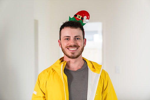 The portrait of a man in casual clothing wearing Santa hat celebrating Christmas looking at camera.