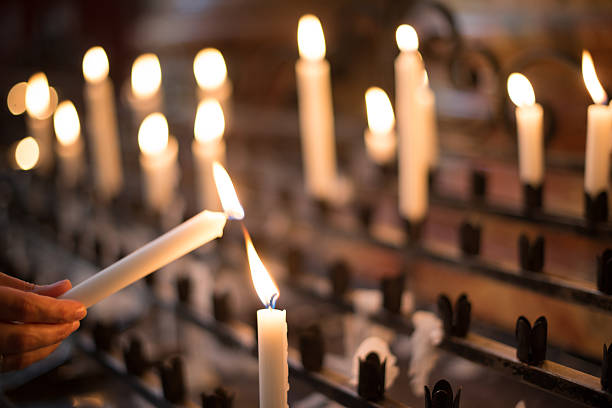 donna di illuminazione candele di preghiera - candela attrezzatura per illuminazione foto e immagini stock