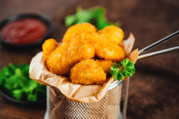 istock Semifinished Breaded chicken nuggets from chicken fillet on a dark background with fresh herbs. Quick cooking at home. Fast food. Breaded Chicken Inner Fillet. Fast cooking.Chicken nuggets with salad. 1795680428
