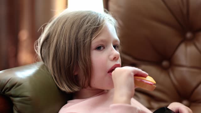 Portrait of child girl eats sausage sandwich with cheese